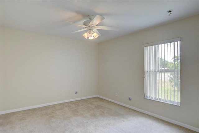 empty room featuring baseboards, light carpet, and a ceiling fan