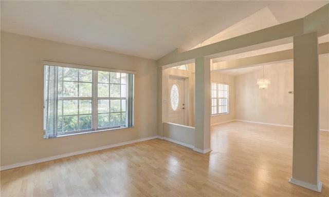 entryway featuring light wood-style floors, vaulted ceiling, baseboards, and a notable chandelier