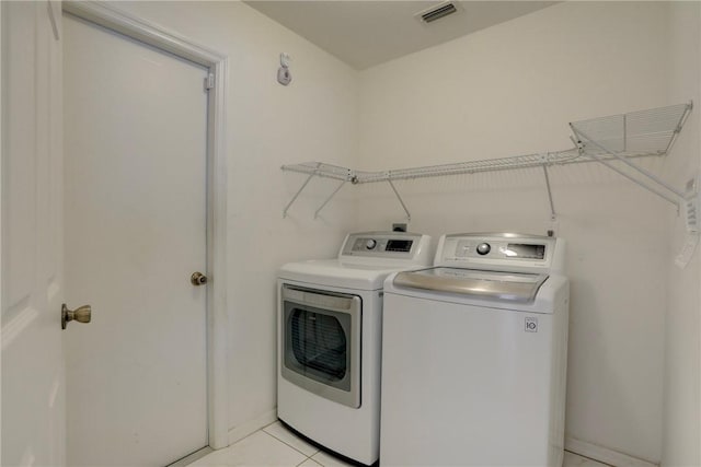 washroom with light tile patterned floors, washing machine and dryer, laundry area, and visible vents
