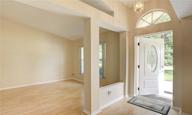 entrance foyer featuring baseboards, a wealth of natural light, a chandelier, and wood finished floors