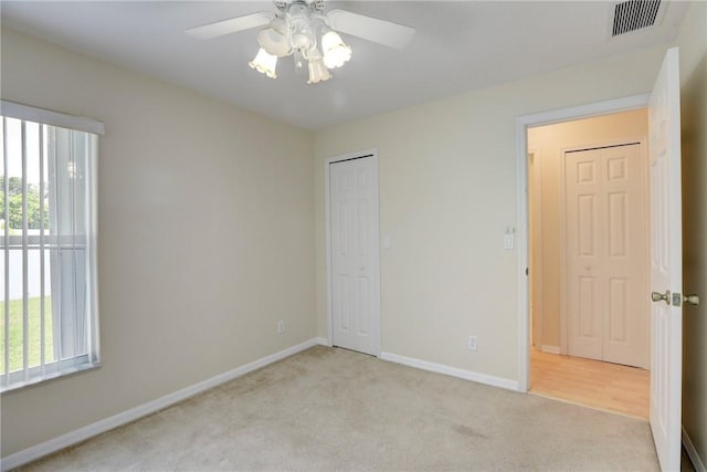 unfurnished bedroom with light colored carpet, visible vents, and multiple windows