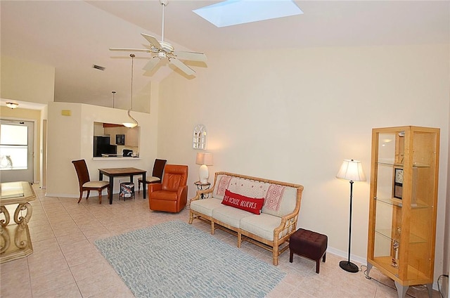 living area with a skylight, ceiling fan, high vaulted ceiling, and light tile patterned flooring