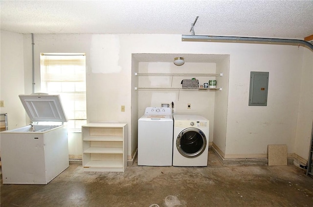 clothes washing area featuring washing machine and clothes dryer, electric panel, and a textured ceiling