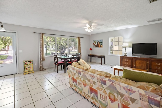 living room featuring a ceiling fan, a textured ceiling, and light tile patterned flooring