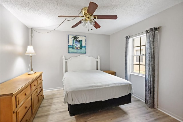 bedroom with a textured ceiling, baseboards, and light wood-type flooring