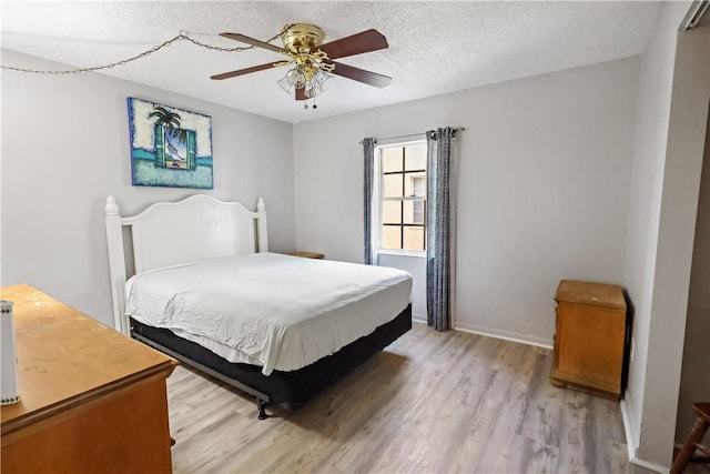 bedroom featuring baseboards, a textured ceiling, ceiling fan, and light wood-style floors