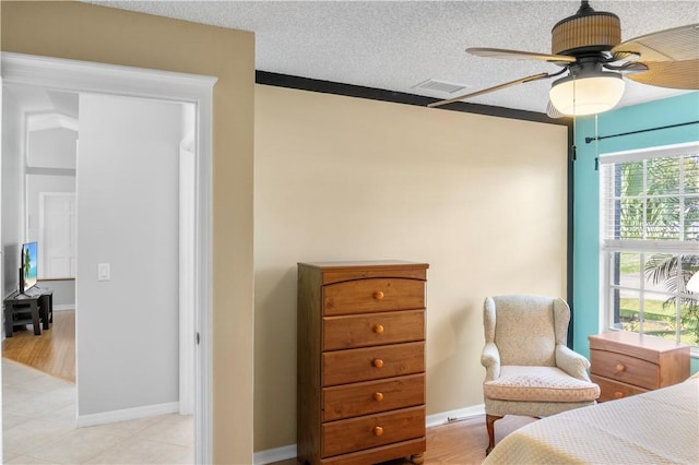 bedroom with baseboards, a textured ceiling, a ceiling fan, and light tile patterned floors