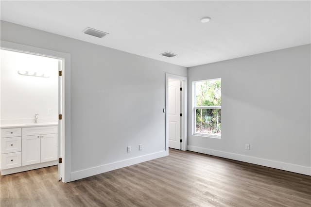 unfurnished bedroom with light hardwood / wood-style flooring, ensuite bath, and sink