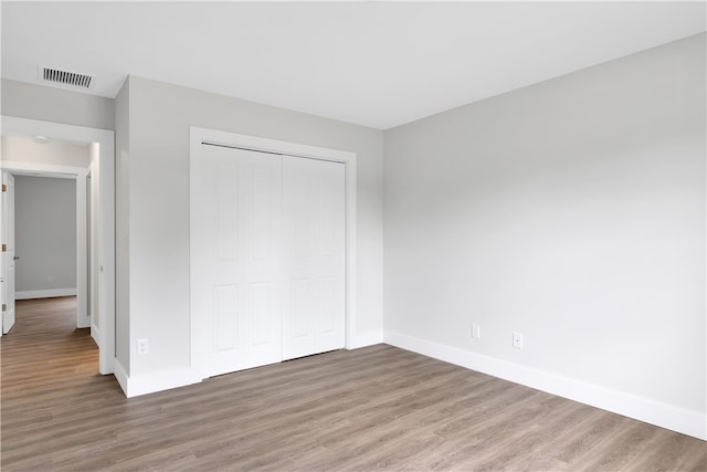 unfurnished bedroom with wood-type flooring and a closet