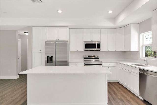 kitchen with a center island, white cabinets, dark hardwood / wood-style floors, light stone counters, and stainless steel appliances