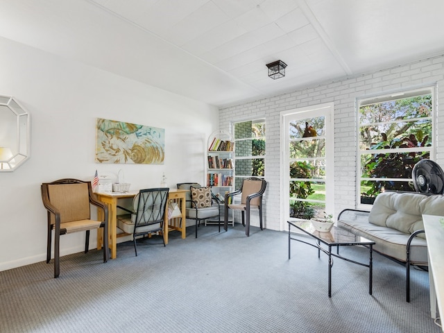 living area with carpet floors and brick wall