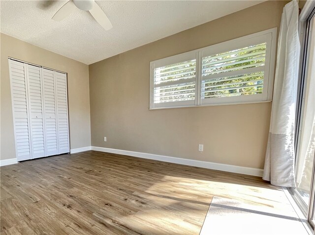 unfurnished bedroom featuring a closet, light wood-type flooring, multiple windows, and ceiling fan