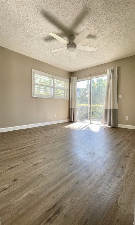 spare room featuring dark wood-type flooring, a textured ceiling, and ceiling fan