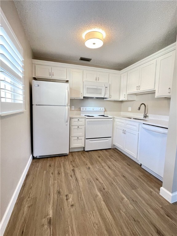 kitchen featuring white cabinetry, white appliances, a textured ceiling, and light wood-type flooring