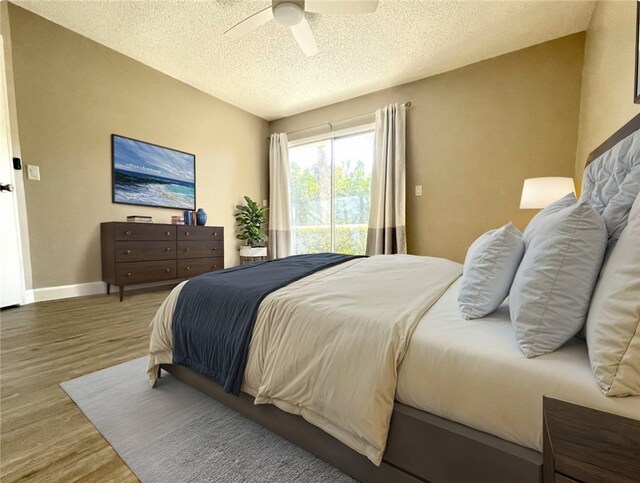 bedroom with hardwood / wood-style floors, ceiling fan, and a textured ceiling