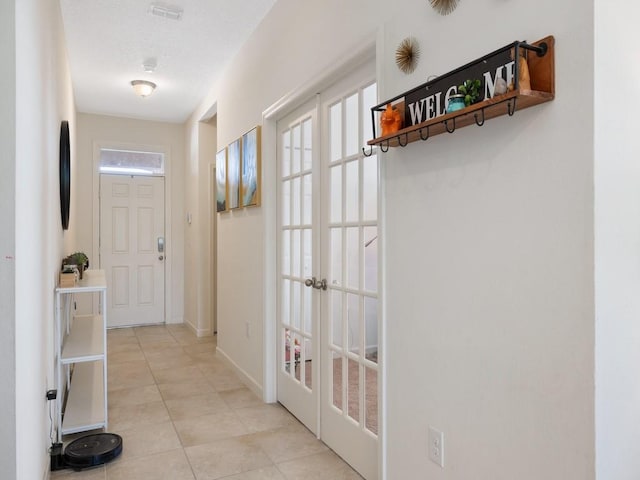 entryway featuring light tile patterned floors, a healthy amount of sunlight, baseboards, and french doors