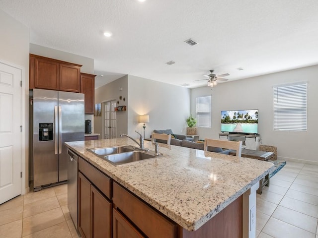 kitchen with visible vents, a center island with sink, a sink, appliances with stainless steel finishes, and light tile patterned flooring