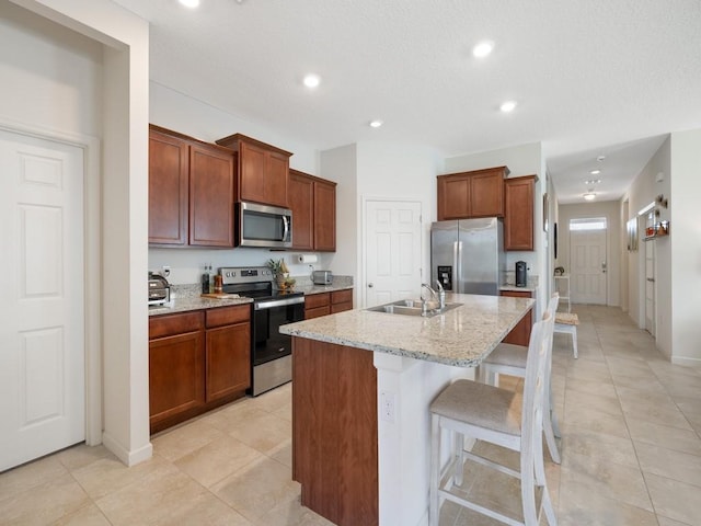 kitchen featuring a sink, recessed lighting, appliances with stainless steel finishes, a kitchen breakfast bar, and a kitchen island with sink