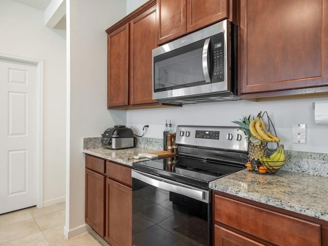 kitchen with light stone counters, light tile patterned flooring, baseboards, and stainless steel appliances