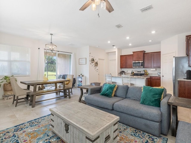 living room with recessed lighting, visible vents, light tile patterned floors, and ceiling fan with notable chandelier