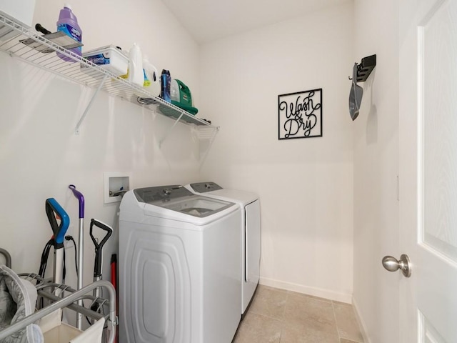 clothes washing area with washing machine and clothes dryer, laundry area, baseboards, and light tile patterned floors