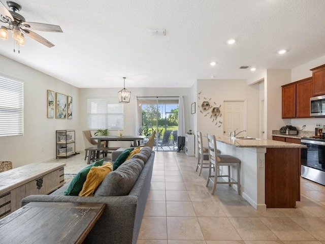 living area with ceiling fan, light tile patterned floors, recessed lighting, and a textured ceiling