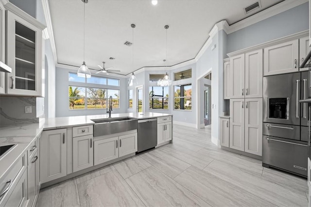 kitchen with appliances with stainless steel finishes, decorative light fixtures, sink, crown molding, and plenty of natural light