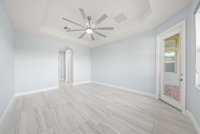 unfurnished room with ceiling fan and a tray ceiling