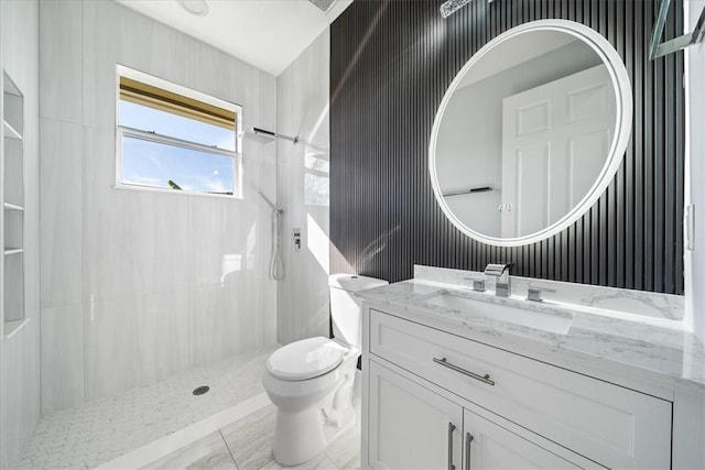 bathroom with tiled shower, vanity, and toilet