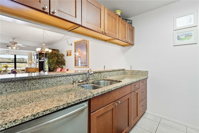 kitchen featuring light stone counters, stainless steel dishwasher, light tile patterned flooring, and sink