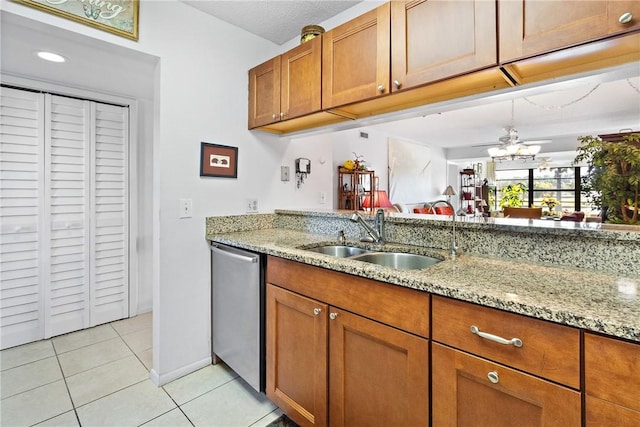 kitchen featuring sink, ceiling fan, light stone counters, light tile patterned flooring, and stainless steel dishwasher