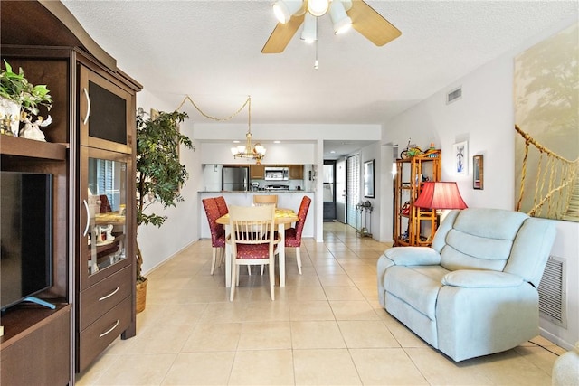 tiled dining room featuring ceiling fan with notable chandelier and a textured ceiling