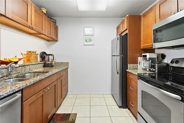 kitchen featuring light stone counters, sink, a textured ceiling, and appliances with stainless steel finishes