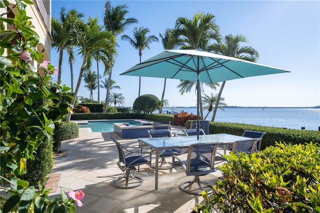 view of patio / terrace with a jacuzzi, a water view, outdoor dining area, and a fenced in pool