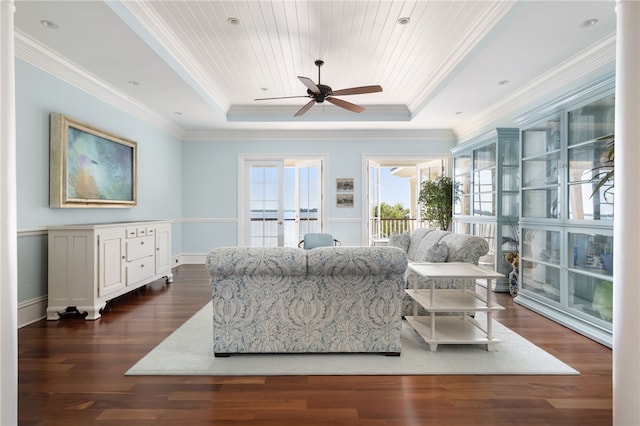 living room featuring dark wood finished floors, a raised ceiling, a ceiling fan, and ornamental molding