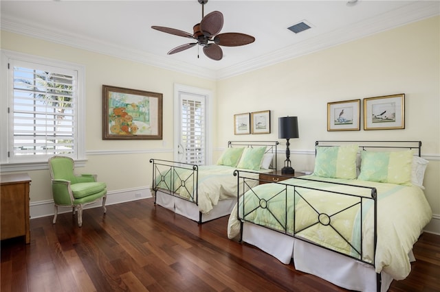 bedroom featuring a ceiling fan, wood finished floors, visible vents, baseboards, and crown molding