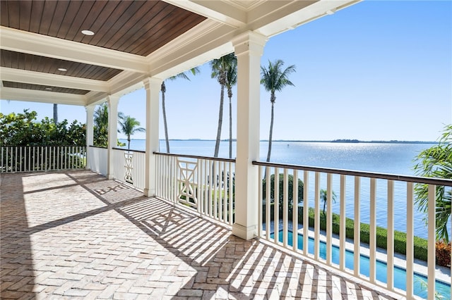 view of patio featuring a balcony, an outdoor pool, and a water view