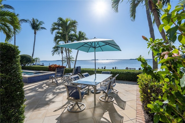 view of patio with outdoor dining space, a hot tub, and a water view