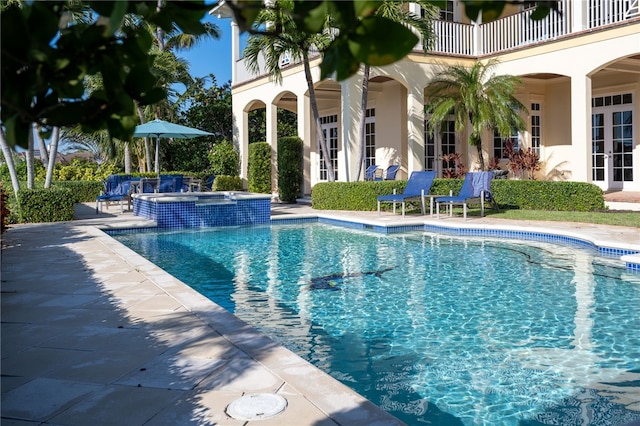 view of swimming pool featuring a patio, french doors, and a pool with connected hot tub