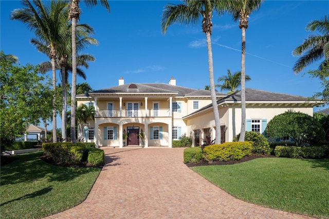 view of front of house featuring a front yard, a balcony, decorative driveway, and stucco siding