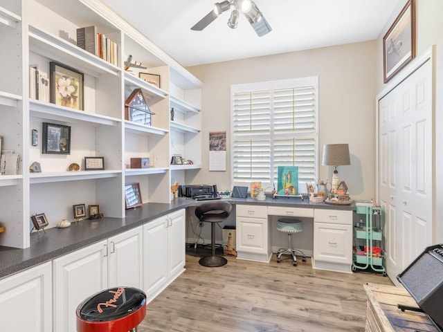 office space featuring ceiling fan, built in desk, and light hardwood / wood-style floors