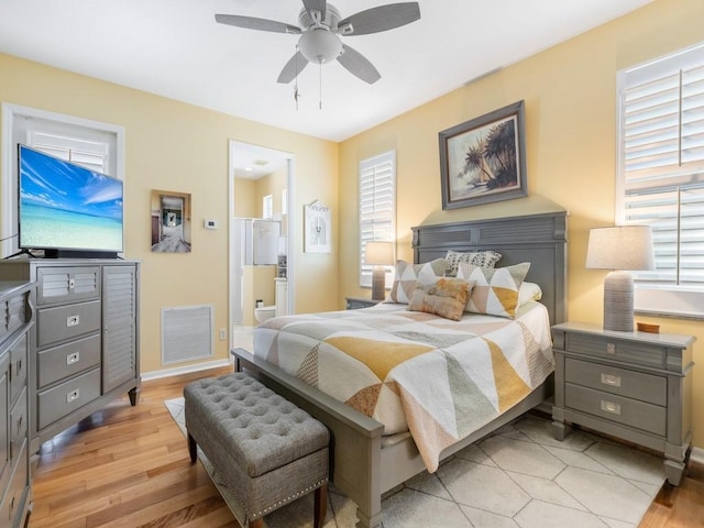 bedroom featuring light hardwood / wood-style flooring, ensuite bath, and ceiling fan