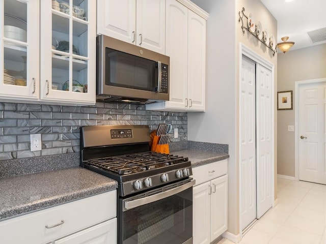 kitchen with decorative backsplash, white cabinetry, light tile patterned floors, and appliances with stainless steel finishes