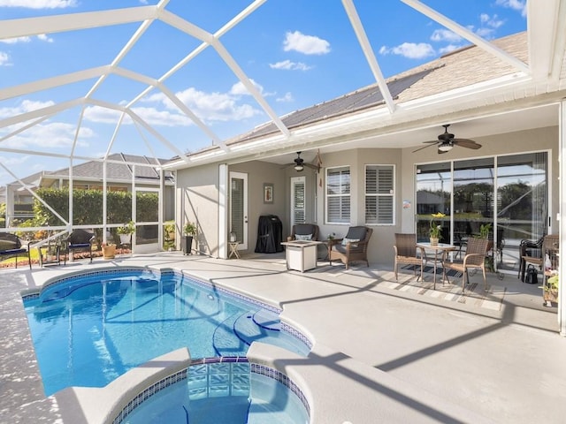 view of pool with an in ground hot tub, glass enclosure, ceiling fan, and a patio area