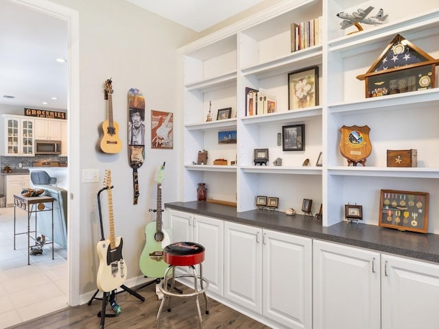 interior space with white cabinets, tasteful backsplash, and dark wood-type flooring