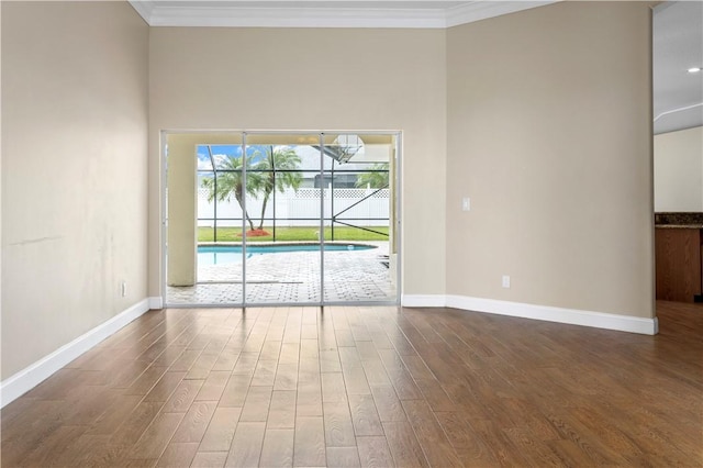 spare room with crown molding, wood-type flooring, and a high ceiling