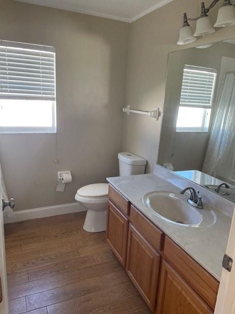 bathroom with vanity, toilet, wood-type flooring, and crown molding