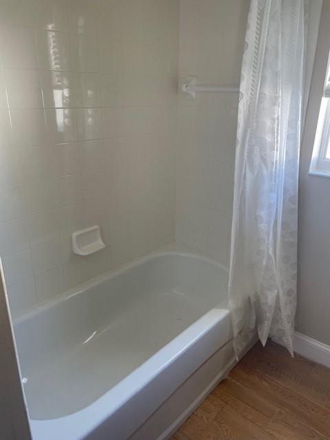 bathroom featuring wood-type flooring and shower / tub combo