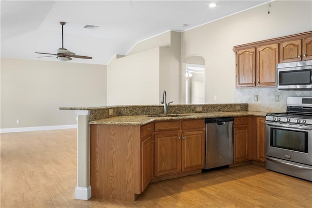 kitchen featuring light stone countertops, stainless steel appliances, ceiling fan, sink, and light hardwood / wood-style floors