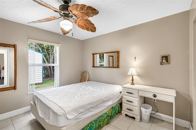 bedroom with light tile patterned flooring, ceiling fan, a textured ceiling, and baseboards